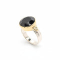 A striking black onyx cut gem rests in a warm gold circle setting on a sleek flat band sterling silver ring