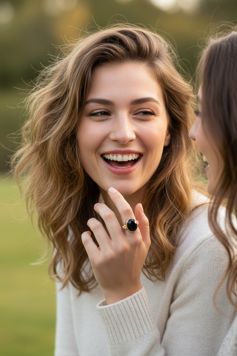A striking black onyx cut gem rests in a warm gold circle setting on a sleek flat band sterling silver ring