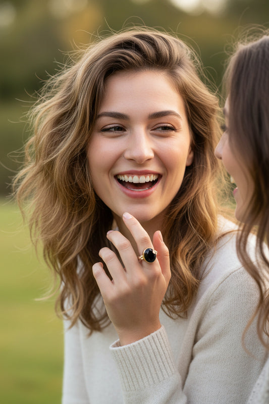 A striking black onyx cut gem rests in a warm gold circle setting on a sleek flat band sterling silver ring