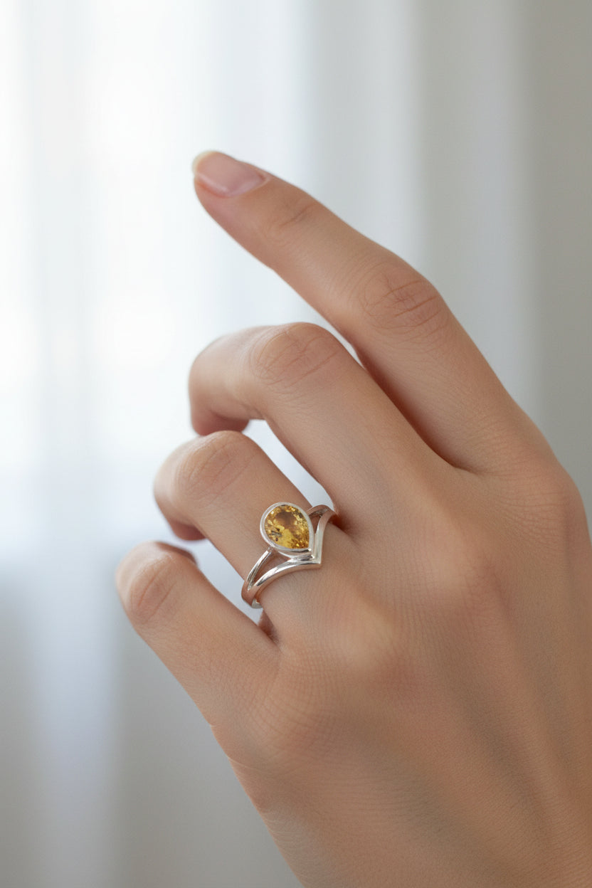 A radiant faceted teardrop citrine ring glows from within a sculptural high-sided sterling silver setting