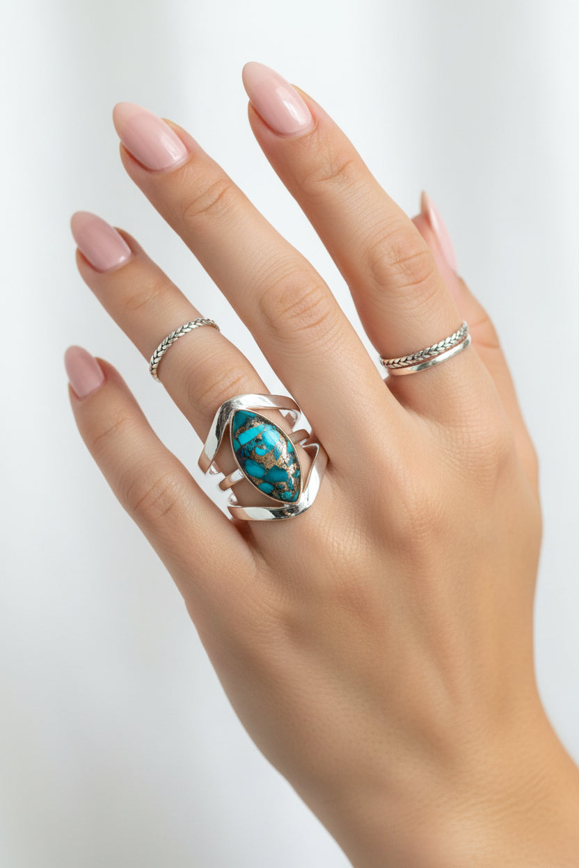Silver ring with a marquise-shaped gemstone featuring blue and green colors on a textured surface.