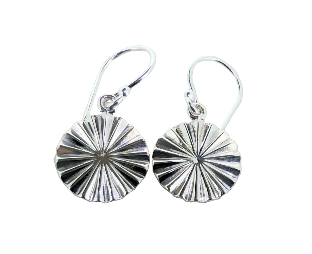 Pair of silver earrings on a textured beige fabric background