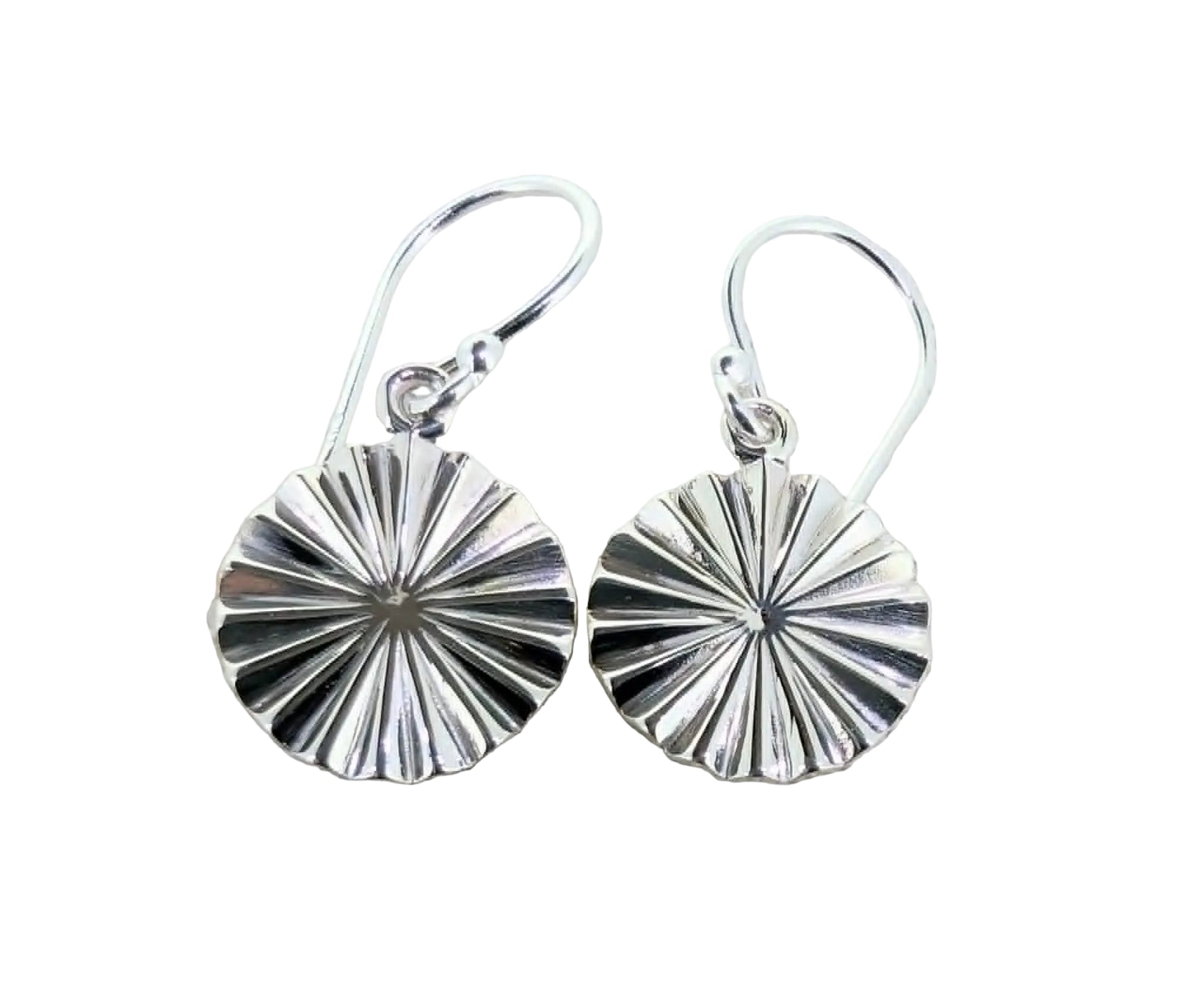 Pair of silver earrings on a textured beige fabric background
