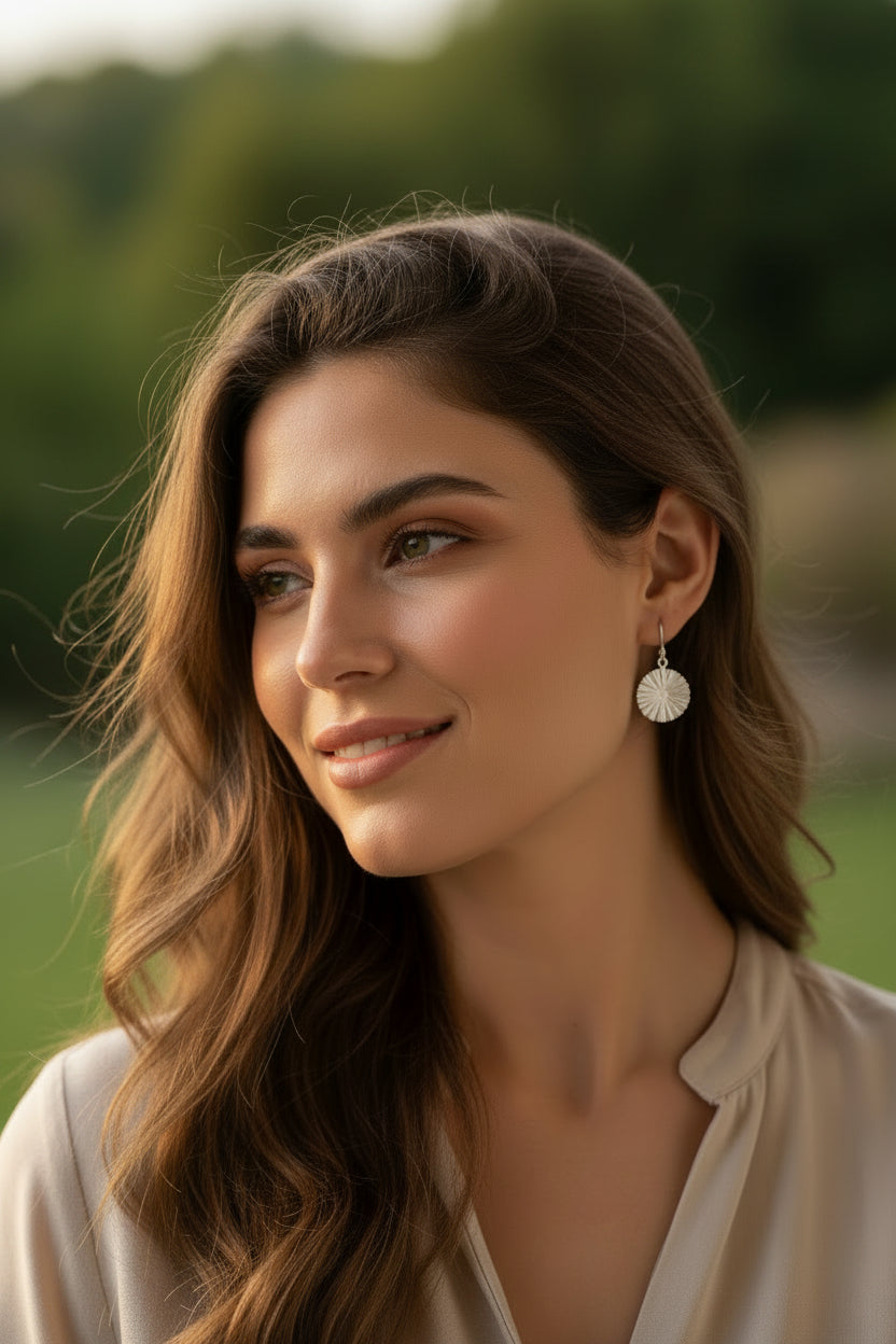 Pair of silver earrings on a textured beige fabric background
