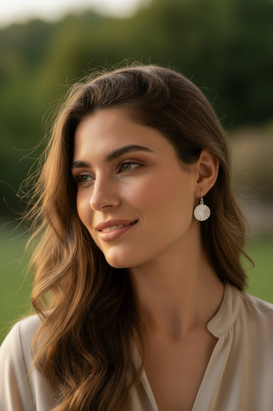 Pair of silver earrings on a textured beige fabric background